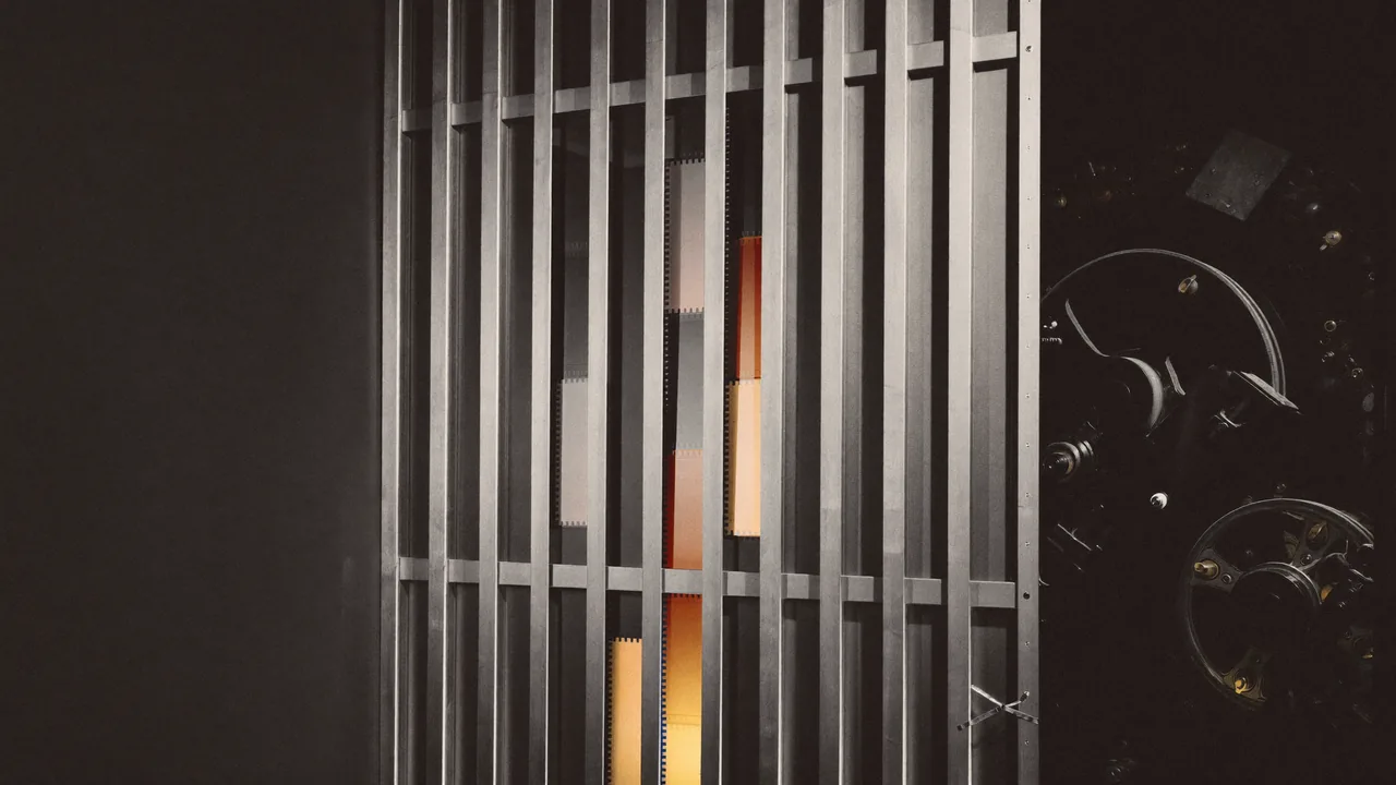 Tall vertical film frames glowing amber behind a steel gate