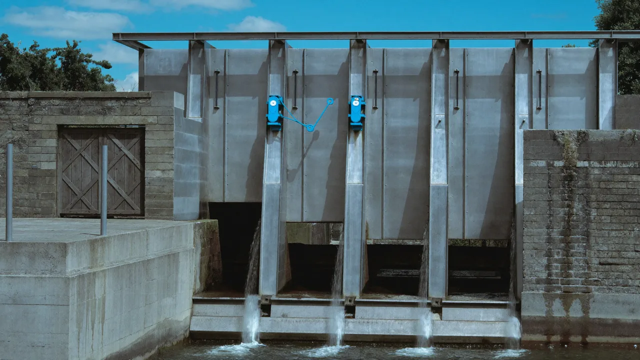 A rebuilt steel lock gate with water pouring through and one azure winding gear